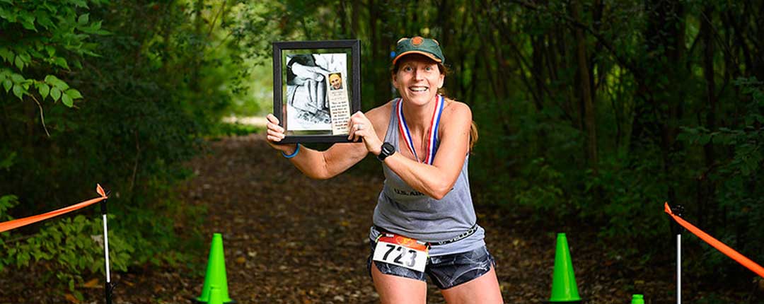 woman in running clothes holding an image on a trail